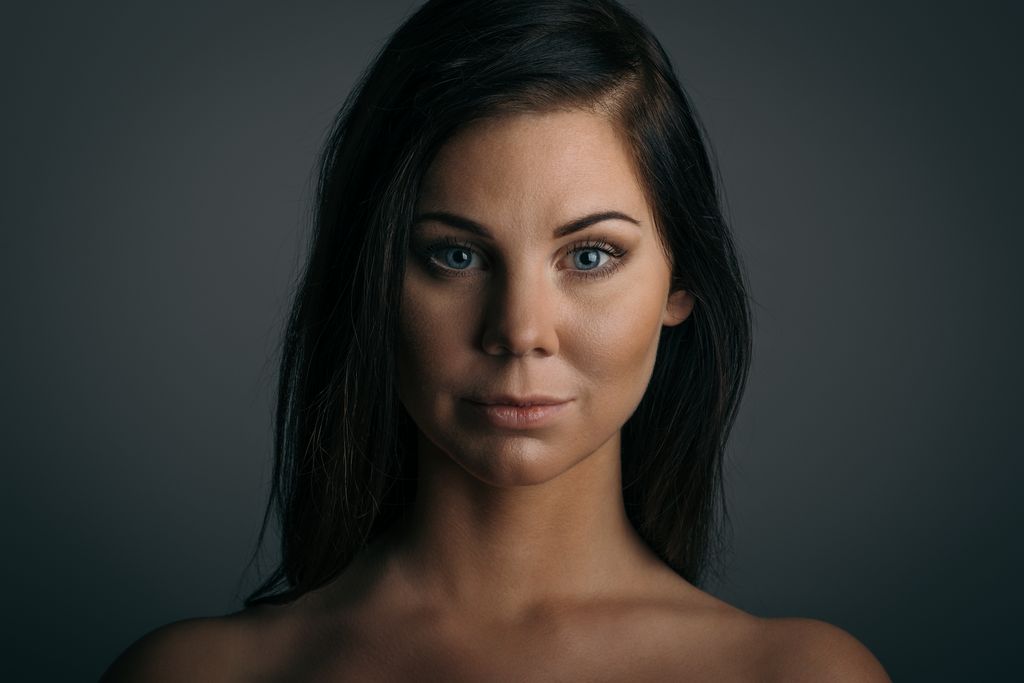 Dramatic studio portrait photography with cinematic lighting featuring brunette woman with blue eyes