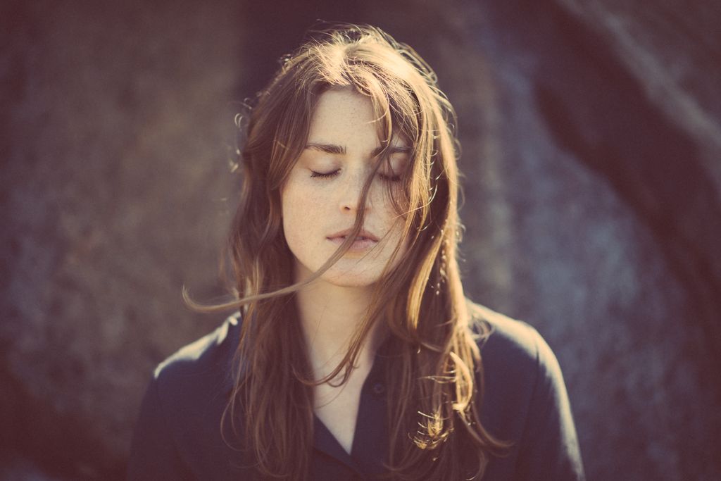 Dreamy natural light portrait photography featuring woman with windblown hair and closed eyes