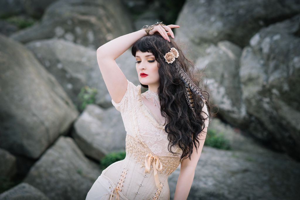 Romantic fantasy portrait photography featuring woman in vintage corset with lace and feathers